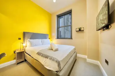 a bedroom with a bed with yellow walls and a window at Stunning Central Station 2 Bed Apartment B4 in Glasgow