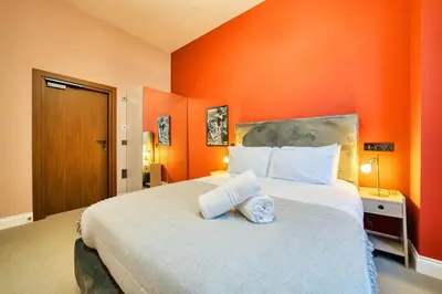 a bedroom with a large bed with an orange wall at Stunning Central Station 2 Bed Apartment B4 in Glasgow