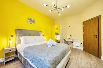 a bedroom with a large bed with yellow walls at Grand Central Station 1 Bed Apartment A5 in Glasgow