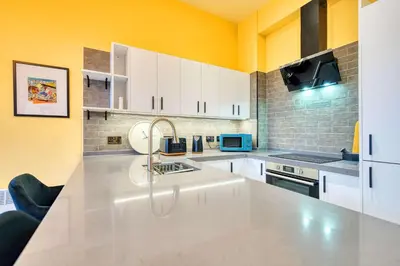 a kitchen with white cabinets and a sink at Lovely Central Station 1 Bed Apartment A6 in Glasgow