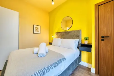 a bedroom with a large bed with a yellow wall at Cozy Central Station 1 Bed Apartment B8 in Glasgow