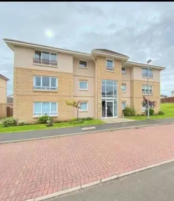 a large apartment building on a brick road at Modern Staycation Apartment in Caldercruix