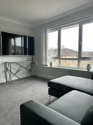 a white room with a bed and a tv and windows at Modern Staycation Apartment in Caldercruix