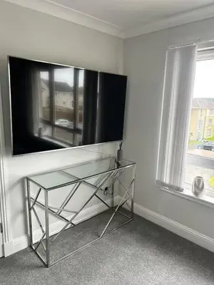 a living room with a tv and a glass table at Modern Staycation Apartment in Caldercruix