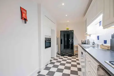 a kitchen with a black refrigerator and a checkered floor at Spacious 3 bed home in Marchmont in Edinburgh