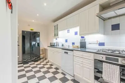 a kitchen with a black refrigerator and a checkered floor at Spacious 3 bed home in Marchmont in Edinburgh
