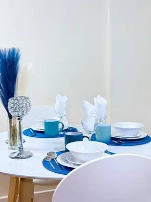 a white table with blue and white plates and glasses at Glasgow City Centre Stylish Flat in Glasgow