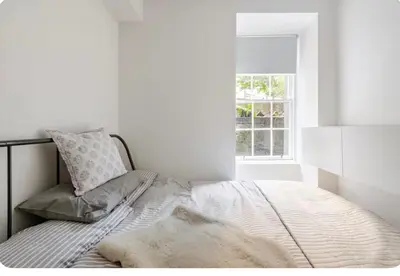 a bed in a white room with a window at The Gardners apartment in City centre with parking in Edinburgh
