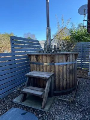 a wooden tub with a wooden bench next to a fence at Callanish Bothy in Benderloch