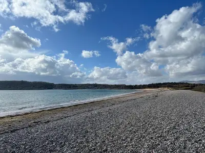 a beach with a cloudy sky and the water at Callanish Bothy in Benderloch