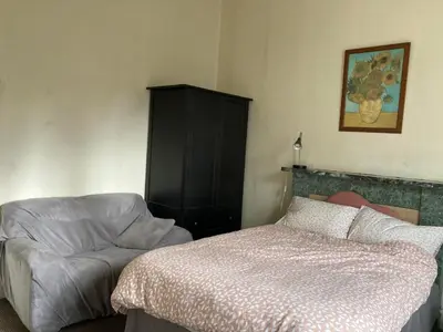 a bedroom with a bed and a chair and a cabinet at Gilmore Flat in Edinburgh