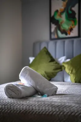 a towel on top of a bed with pillows at Caledonia Apartment in South Cobbinshaw