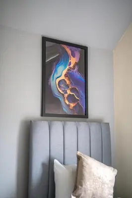 a painting on the wall above a blue couch at Caledonia Apartment in South Cobbinshaw