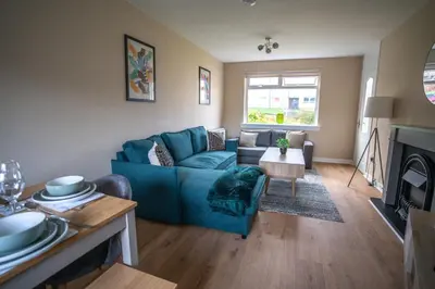 a living room with a blue couch and a fireplace at Castlefern House in Rutherglen