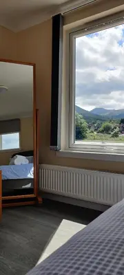 a bedroom with a bed and a large window at Barra Cottage in Ballachulish