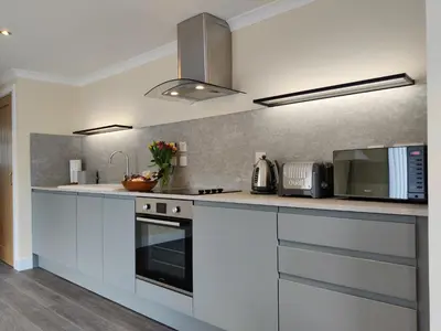a kitchen with white cabinets and a stove top oven at Barra Cottage in Ballachulish