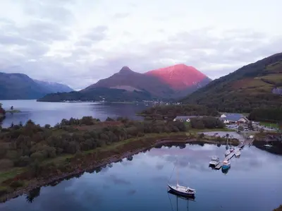 an aerial view of boats in a lake with mountains at Barra Cottage in Ballachulish