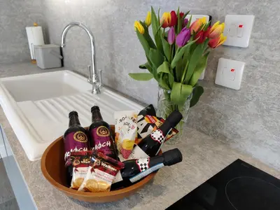 a basket of wine and flowers on a kitchen counter at Barra Cottage in Ballachulish