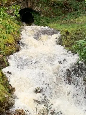 a stream of water in front of a tunnel at Tumpseys Hideaway with Hot Tub & Sunset Loch Views, Glencoe Near Fort William in Ballachulish