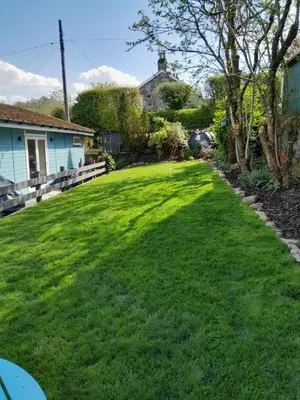 a yard with green grass and a house at Wee Blue Hoose in Dalmally