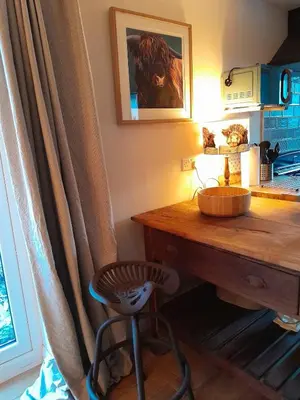 a room with a desk with a stool and a table at Wee Blue Hoose in Dalmally