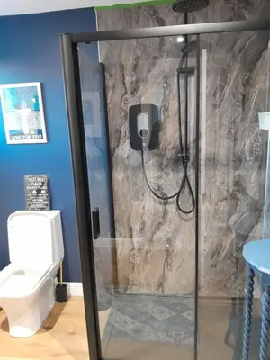 a shower in a bathroom with a stone wall at Wee Blue Hoose in Dalmally