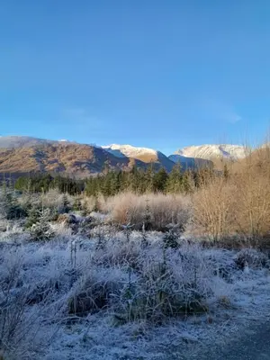 a field covered in snow with mountains in the background at Wee Blue Hoose in Dalmally