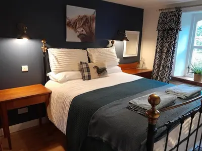 a bedroom with a large bed with white pillows at Wee Blue Hoose in Dalmally