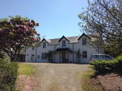 a white house with a car parked in the driveway at Strathwhillan House in Brodick