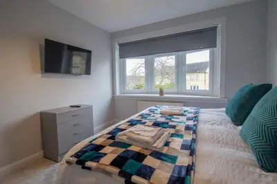 a bedroom with a bed and a tv and a window at Kerr Apartment-Spacious 4-Bed Flat in Hamilton, Close to Glasgow in Cadzow