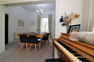 a dining room with a table and a piano at 10 Bedrooms Pool Table Garden Piano in Glasgow