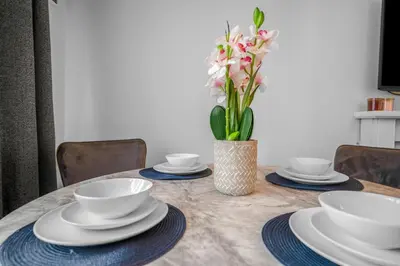 a table with plates and bowls and a vase of flowers at 3 Bedrooms Homely House in Motherwell Sleeps 8 comfortably with 6 double beds Near Glasgow Edinburgh Free Private Parking Business Travellers Contractors Holiday Goers Near all Major transport links in Carfin