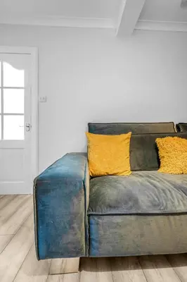 a blue couch with yellow pillows in a living room at 3 Bedrooms Homely House in Motherwell Sleeps 8 comfortably with 6 double beds Near Glasgow Edinburgh Free Private Parking Business Travellers Contractors Holiday Goers Near all Major transport links in Carfin