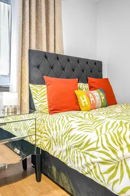 a bed with colorful pillows on it in a room at 3 Bedrooms Homely House in Motherwell Sleeps 8 comfortably with 6 double beds Near Glasgow Edinburgh Free Private Parking Business Travellers Contractors Holiday Goers Near all Major transport links in Carfin