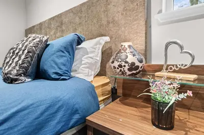 a bed with blue sheets and a vase on a table at Westcraigs in Westfield