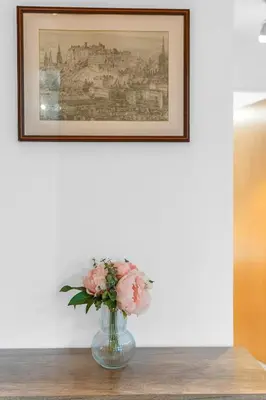 a vase with pink flowers on a table under a picture at Modern 2 bedroom apartment in City Centre in Edinburgh