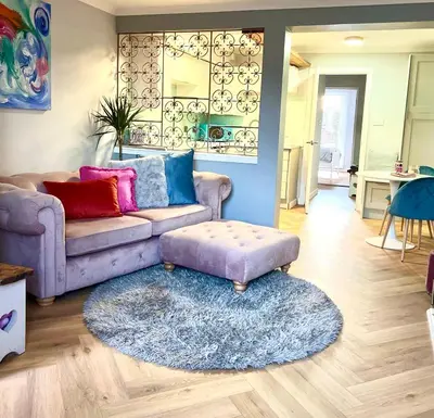 a living room with a couch and a ottoman at Tin Lid Cottage - cosy ground floor flat in Banton