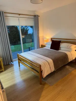 a bedroom with a large bed and a large window at Spacious & Modern Garden Apartment in Bearsden