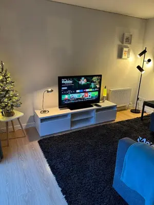 a living room with a flat screen tv on a cabinet at Spacious & Modern Garden Apartment in Bearsden