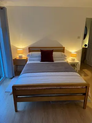 a bedroom with a large bed with two lamps on two tables at Spacious & Modern Garden Apartment in Bearsden