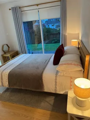 a bedroom with a large bed with a large window at Spacious & Modern Garden Apartment in Bearsden