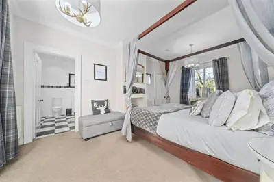 a bedroom with a large bed and a chair at The Strone Luss Premium Holiday Rental in Luss