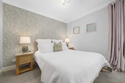 a bedroom with a large white bed and two lamps at The Strone Luss Premium Holiday Rental in Luss