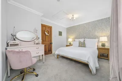a bedroom with a bed and a mirror and a chair at The Strone Luss Premium Holiday Rental in Luss