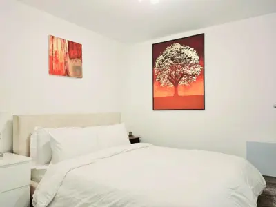 a bedroom with a white bed and a tree on the wall at Cozy Flat in Glasgow City Centre in Glasgow