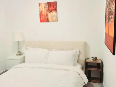 a bedroom with a bed with white sheets and a table at Cozy Flat in Glasgow City Centre in Glasgow