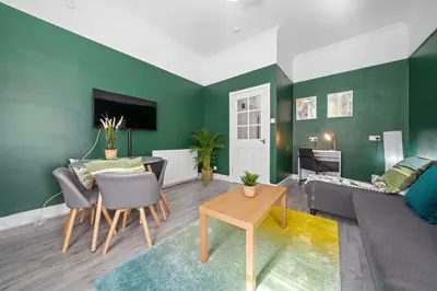 a living room with green walls and a couch and a table at Central Kirkintilloch 2 Bed App in Kirkintilloch