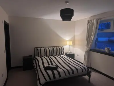 a bedroom with a striped bed with a window at Langside apartments 2 in Newhouse