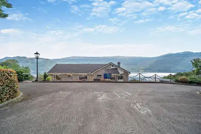 a house on a road with a view of a lake at 4 Bed in Lochgoilhead oc-j30107 in Carrick