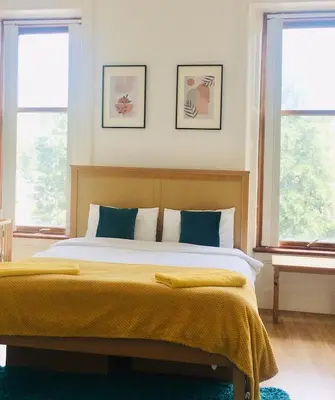 a bedroom with a bed with yellow sheets and two windows at VS-Entire Flat-Central Scotland-Falkirk, Self-Check-in , Pet-friendly with Parking in Falkirk